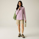 Full-length view of a model wearing a lilac half-zip fleece with beige shorts, hiking shoes and a backpack, holding a water bottle.