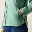 Detail close-up of the green fleece jacket, showing the zipped side pocket and hem.
