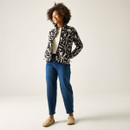 Full-length view of model wearing the cream-and-black floral print fleece jacket with blue jeans and beige slip-on shoes.