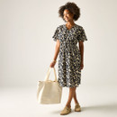 Full-length shot of the model in the cream and navy floral print dress, carrying a large cream tote bag and wearing neutral slip-on shoes.