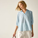 Model wearing a light blue, white pinstripe blouse with a V-neck collar and three-quarter sleeves, styled with white trousers.