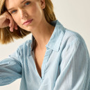 Close-up of the light blue pinstripe blouse showing the V-neck collar and fabric texture.
