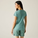 Back view of the model wearing the green short-sleeve T-shirt with matching green shorts.