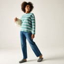 Model wearing a green and white striped long-sleeve top with blue jeans, holding a cream bag.