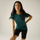 Model wearing a blue short-sleeved T-shirt with black hiking shorts and a black headband, leaning forward in a studio setting.