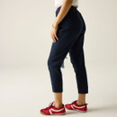 Rear three-quarter view of a model wearing navy cropped trousers with red trainers.