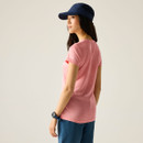Rear three-quarter view of woman wearing the peach marl short-sleeve T-shirt and blue shorts, with a navy cap.