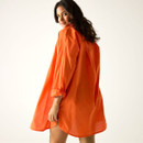 Rear view of orange long-sleeve shirt worn as a beach cover-up.