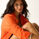 Close-up portrait of model wearing an orange shirt over a striped swimsuit.