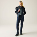 Full-length view of a navy hybrid padded jacket worn with walking trousers, boots and a backpack.