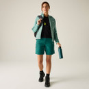 Full-length front view of the green hooded insulated jacket worn with green outdoor shorts and hiking boots.