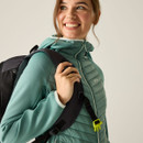 Three-quarter view of the green hooded jacket worn with a backpack, showing insulated body and stretch sleeves.