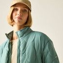 Close-up of the model wearing a green quilted jacket, showing the high collar, zip front and sleeve branding.
