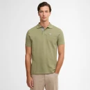 Young man wearing a light green polo shirt with subtle checked detail and beige pants. The background is a plain white, conveying a casual tone.