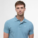 Man with short brown hair wears a light blue polo shirt and neutral expression. Plain white background highlights the clothing and his calm demeanour.