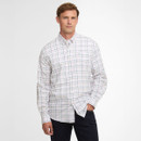 Man in a white button-up shirt with pink and black plaid pattern, hands in pockets, standing against a plain white background, looking relaxed.