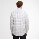 A person is seen from behind wearing a white plaid shirt with multicoloured lines and dark jeans, standing against a plain white background.