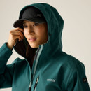 Close-up of a woman wearing a blue hooded waterproof jacket, showing the adjustable hood and front zip detail.