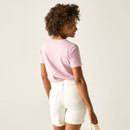 Rear view of a woman wearing a light pink short-sleeve T-shirt and white shorts, showing the plain back of the T-shirt.