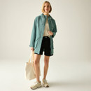 Women’s ivy moss green hooded waterproof jacket styled with shorts, full-body view.