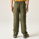 A person is wearing olive green hiking pants with zip-off legs, viewed from the back. They also wear tan shoes and a yellow shirt, standing on a plain background.
