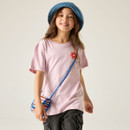 A smiling child wears a pink t-shirt with a red flower, a blue hat, and a colourful knitted purse. The background is plain, conveying a playful tone.