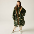 Young girl wearing a green coat with a horse pattern, beige lining, and a green robe. She pairs it with beige pants and white sneakers, smiling confidently.
