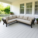 A cosy L-shaped beige sectional sofa on a white porch with green potted plants and a lush garden view, conveying tranquillity and comfort.