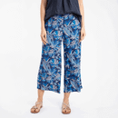 Woman wearing navy blue wide-leg cropped trousers with a blue and white tropical leaf print, paired with sandals.