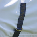 Close-up of a Shires branded adjustable strap and metal slider on a white horse fly rug.
