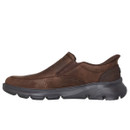 Brown leather slip-on shoe with visible stitching, featuring a rounded toe and black cushioned sole. The design is sleek and casual.