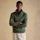 Model wearing a green quarter-zip fleece with a high collar and cream trousers, standing against a neutral background.