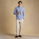 Model wearing a blue and white gingham button-down shirt with beige trousers, shown full length from the front.