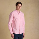 Close-up of a pink gingham button-down shirt showing the collar, buttons and chest pocket with embroidered hare logo.