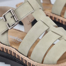 Close-up of the green straps and metal buckle on the platform sandal, showing the stitched detailing and textured upper.