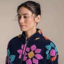 Close-up of model wearing navy fleece jacket, showing high collar and textured floral detailing