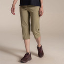 Woman wearing khaki knee-length outdoor cropped trousers with hiking shoes, walking in studio.