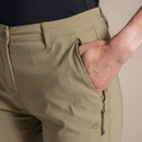 Close-up of khaki cropped trousers zip pocket with hand inside and embroidered logo detail.
