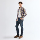 Full-body view of model wearing a blue and beige plaid western shirt over a white T-shirt with dark blue jeans and brown shoes.