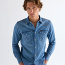 Front view of model wearing a mid-light wash denim western shirt with snap buttons and flap chest pockets.