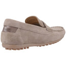 A beige suede loafer with visible stitching, shown from the rear angle. The shoe has a textured rubber sole and a leather detail at the heel, conveying a casual, sophisticated style.