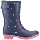 A navy blue rubber boot with pink and white polka dots, featuring a pink sole and a side buckle. The design is playful and cheerful.