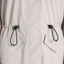 Close-up of the front drawcord waist adjusters with black toggles on a light grey Craghoppers long waterproof coat.