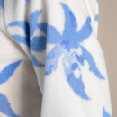 Close-up of sleeve detail on an off-white blue floral fleece, showing embroidered leaf logo on the arm.