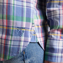 Close-up of the shirt hem showing the woven side label and check pattern, styled over blue denim jeans.