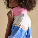 Side profile close-up of model holding the raised pink collar on a Joules striped rugby polo top, showing the textured fabric stripes.