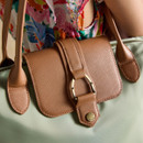 Close-up of the tan leather flap and gold-tone buckle detail on the sage green Joules tote bag.