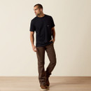 Full-body view of a model wearing a black pocket T-shirt with brown work pants and brown shoes on a beige studio background.