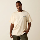 Front view of a model wearing the sand-colored T-shirt with a small “Ariat” logo on the left chest and olive shorts.