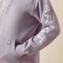 Close-up of the hoodie sleeve showing the large “ARIAT” logo print and ribbed cuff above the pocket.